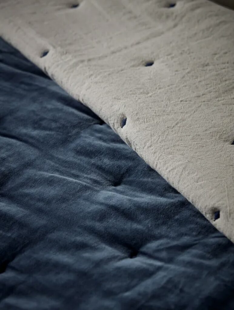 Close-up of reversible velvet and cotton linen quilt in a blue bedroom – blue bedroom ideas
