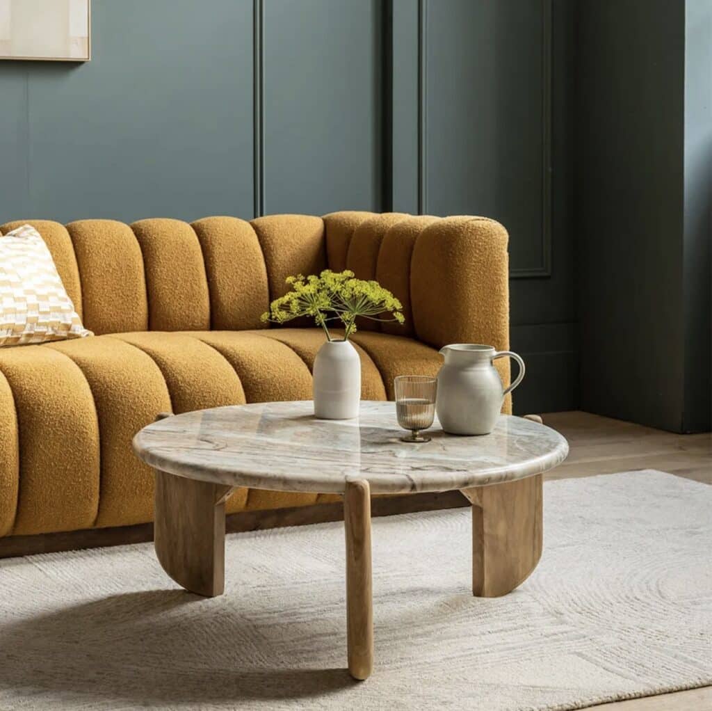 Mustard sofa with cream rug and marble coffee table for a warm, neutral-toned living room scheme