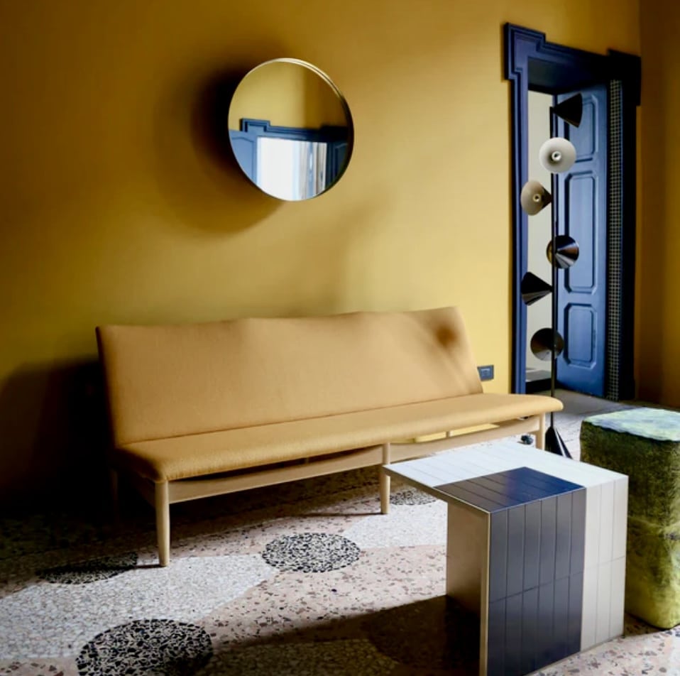Mustard living room with mustard-yellow walls, pale wood sofa and deep navy door for contrast.