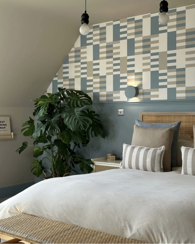 Geometric colour block wallpaper feature wall in a sloped bedroom ceiling