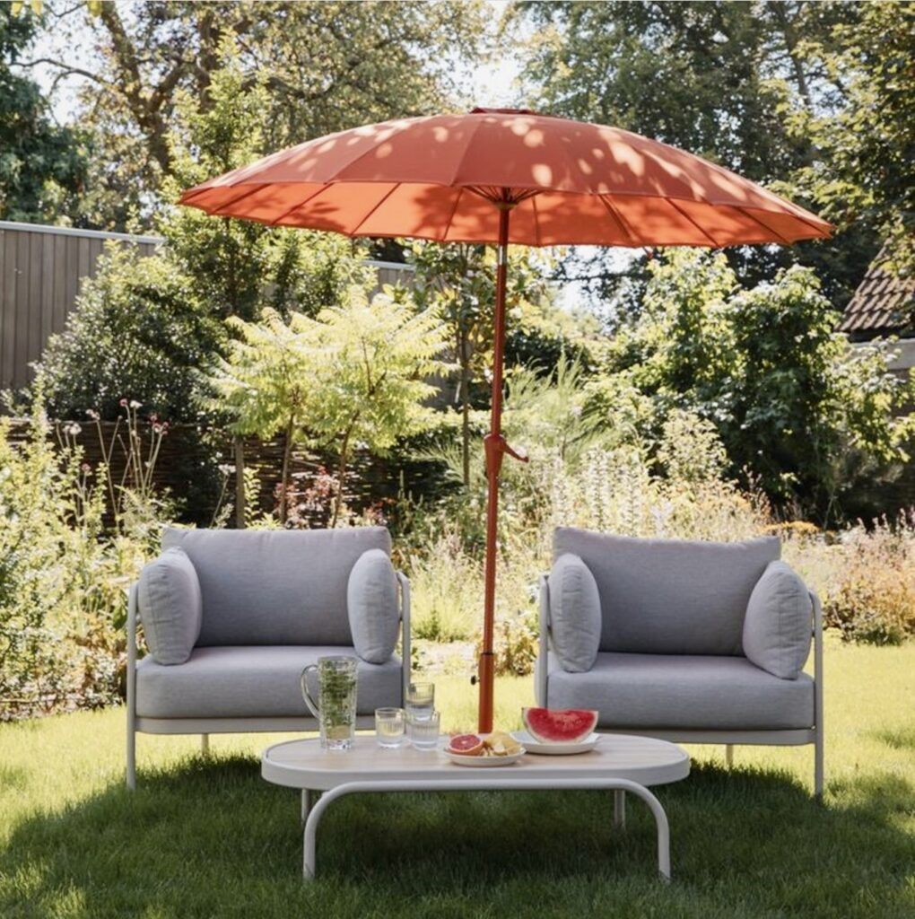 Terracotta burnt orange garden parasol paired with grey outdoor seating – a bold and stylish addition to burnt orange home décor for outdoor living spaces