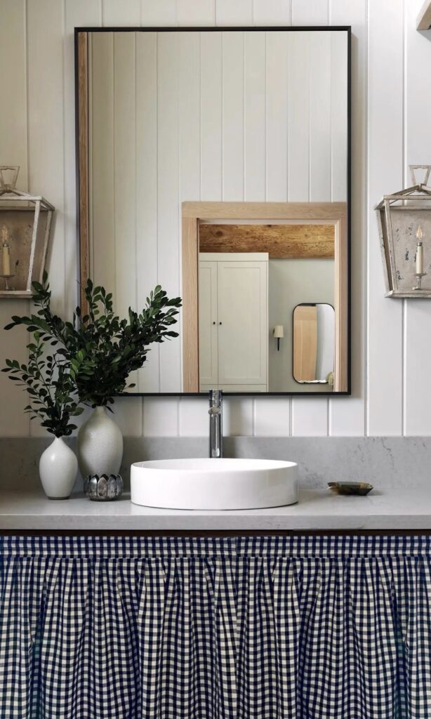 Navy gingham sink skirt hiding under-basin storage in a small bathroom