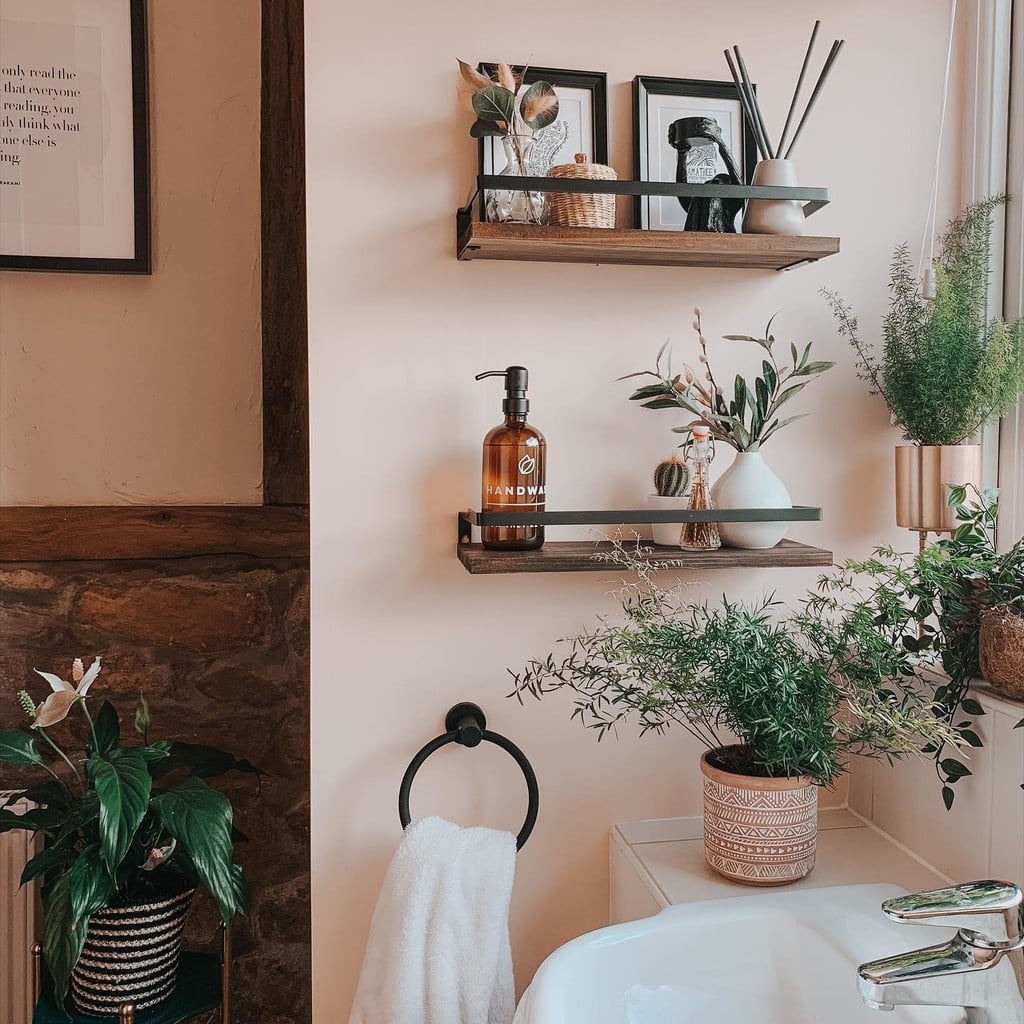 Open wooden shelving with plants and glass bottles as a low-cost alternative to bathroom cabinetry
