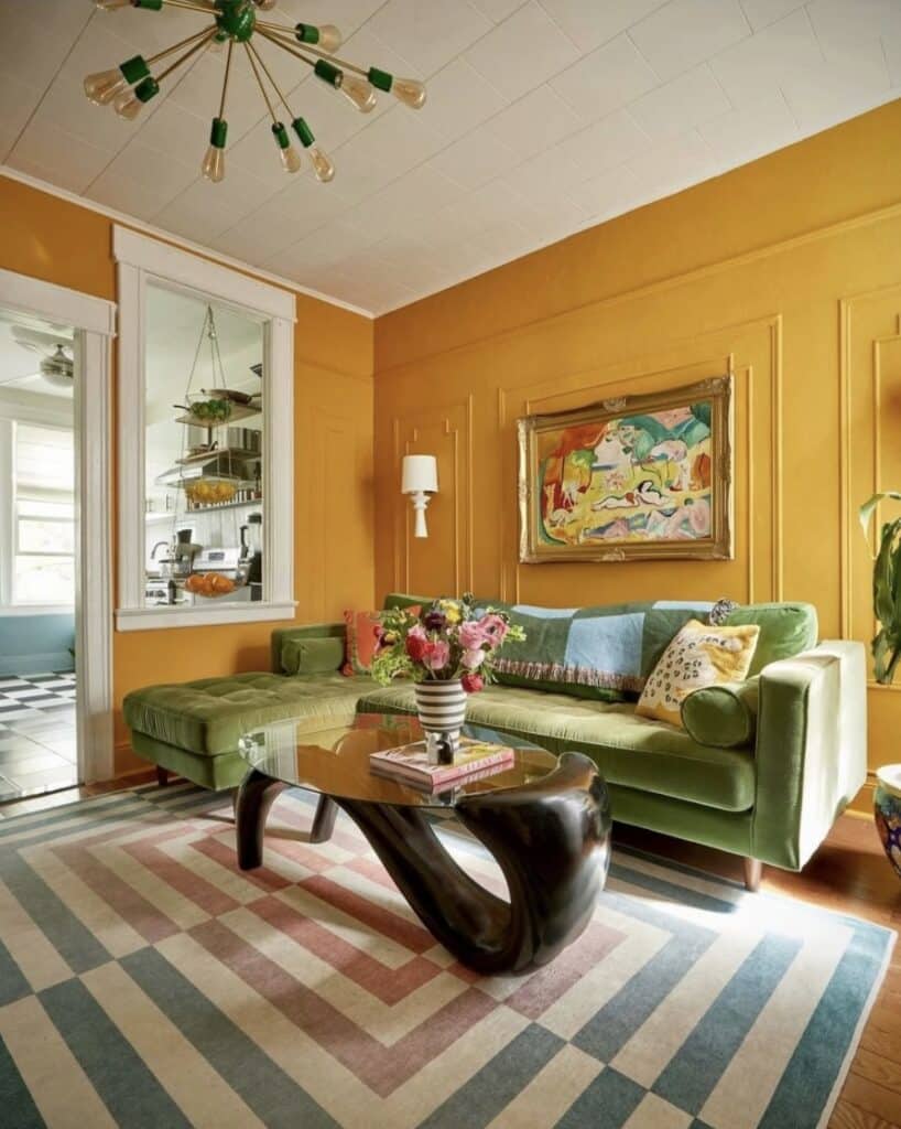Dutch Orange (burnt orange) living room with an olive-green velvet sectional, sculptural black coffee table and geometric rug.