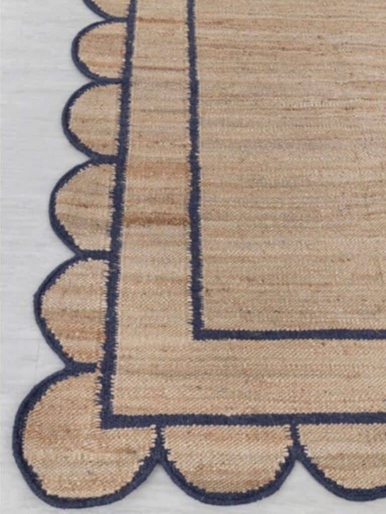 Close-up detail of navy bordered scalloped jute rug showing curved edge