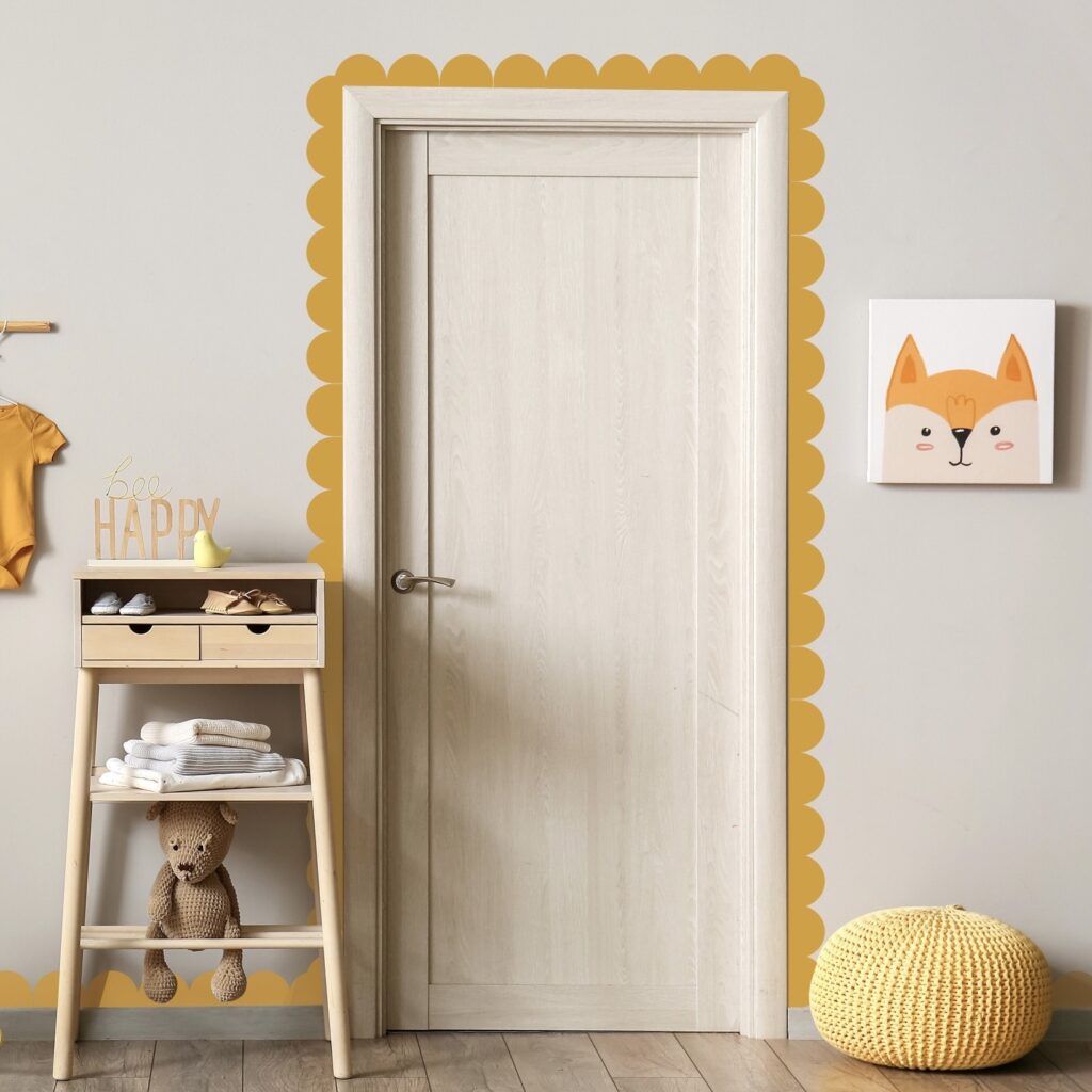 Mustard yellow scalloped edge wall border framing a door in a playful nursery setting