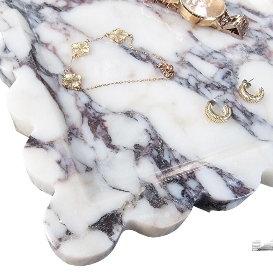 Scalloped edge marble tray with jewellery and a watch, styled as a bedside catch-all.