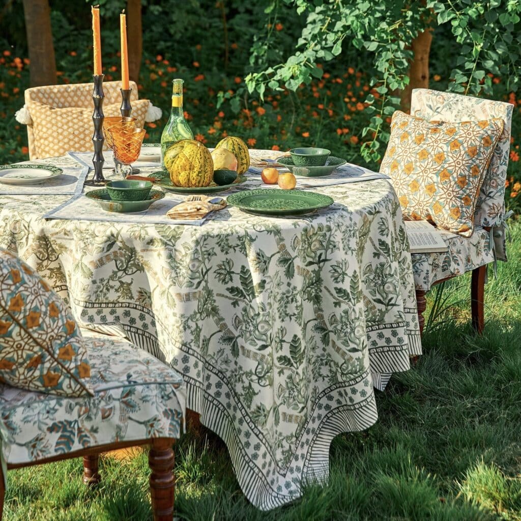 outdoor spring table setting with green floral tablecloth and candles in garden