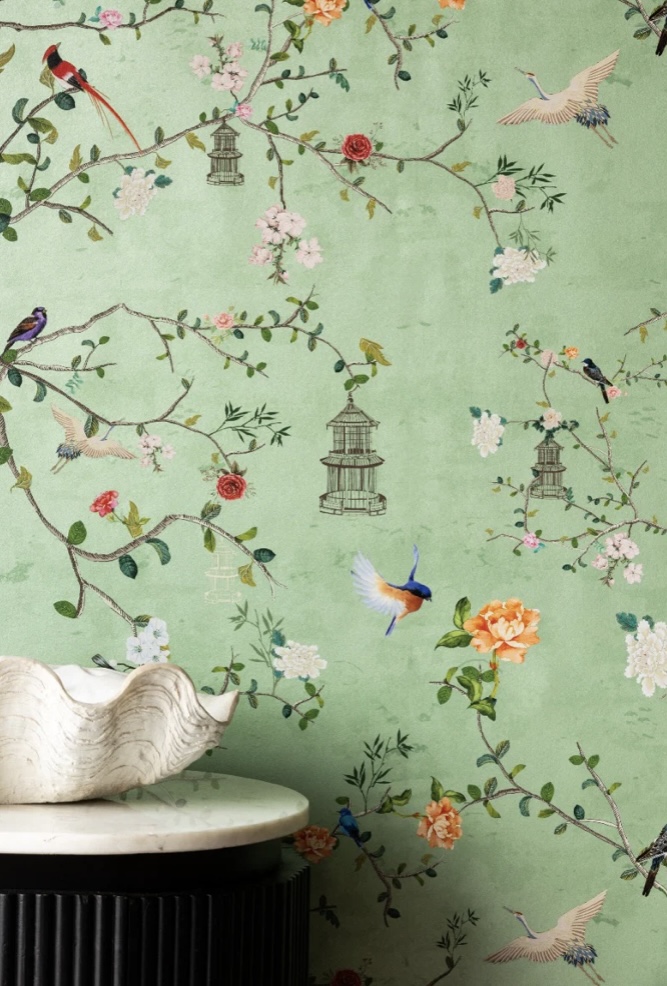 Green floral wallpaper in a chinoiserie style featuring delicate birds and branches on a tea green background.