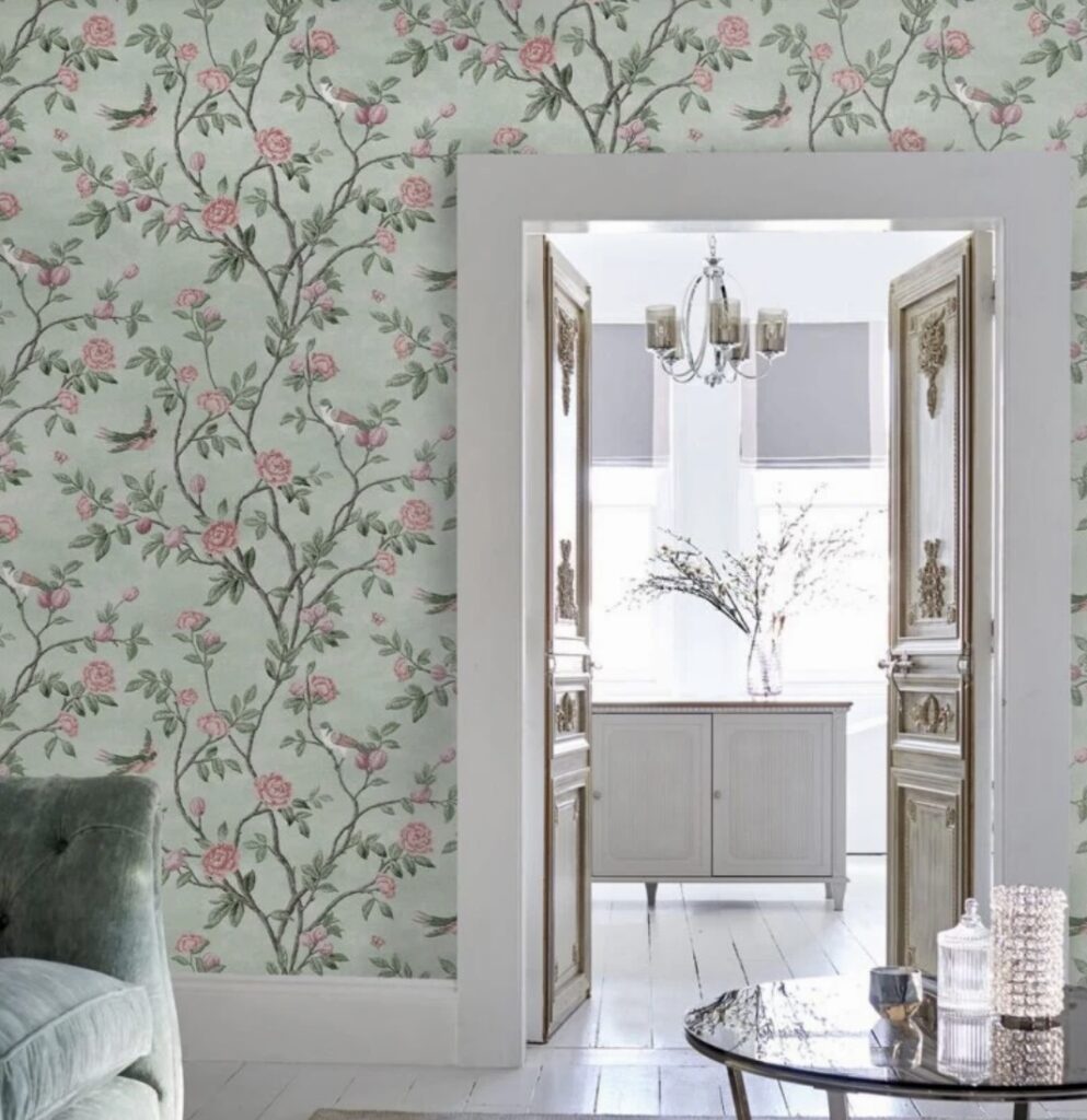 Green floral wallpaper with pink roses in an elegant hallway with vintage double doors and white interior.