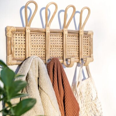Handcrafted rattan wall hooks with woven cane detail holding coats and bags