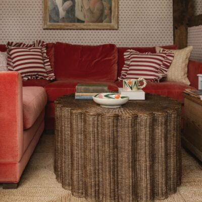 Scalloped rattan coffee table with artisan ceramics in a cosy red living room