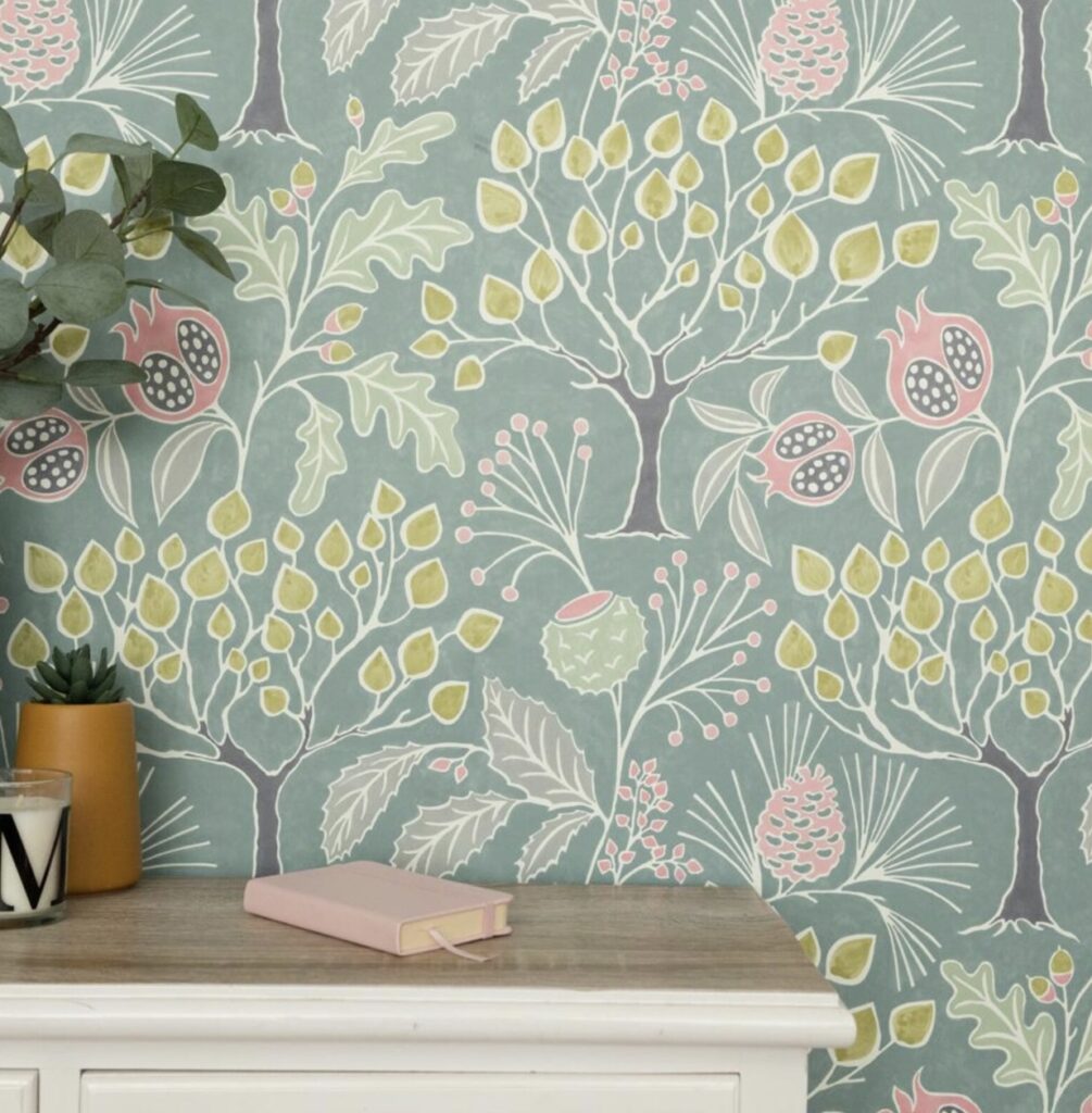Whimsical green floral wallpaper with pink pomegranates and yellow acorns styled with a small console table.