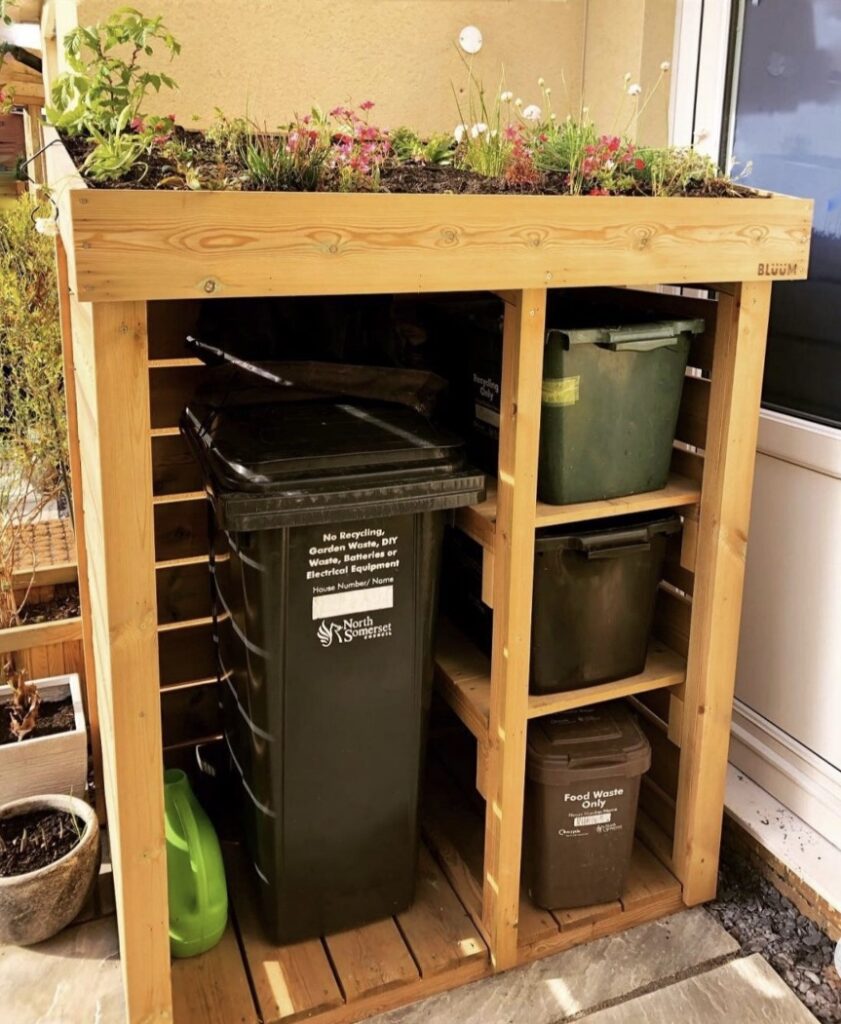 Wooden wheelie bin storage with recycling compartments and a planted green roof – compact and eco-friendly storage idea