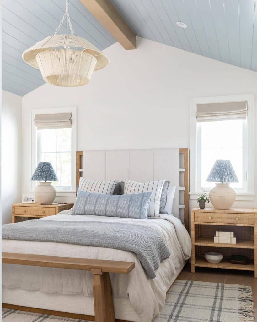 Parma Gray painted ceiling in a coastal bedroom with rattan pendant light, oak bedside tables and striped linen bedding — @aliciatorosiandesign. Image credit: Farrow & Ball.
