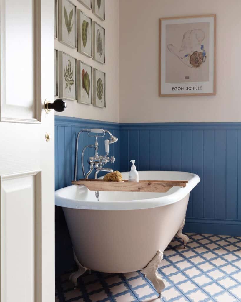 Farrow & Ball Cook’s Blue tongue and groove panelling with roll-top bath, patterned encaustic floor tiles and botanical prints — @studiofantoush. Image credit: Farrow & Ball.