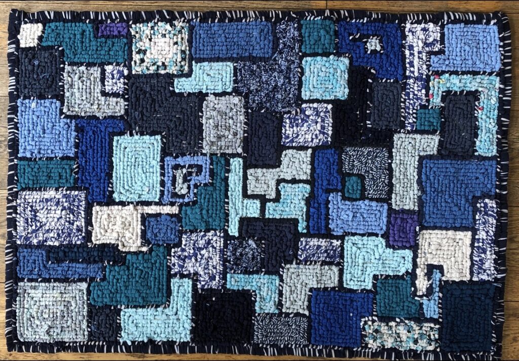 Geometric blue rag rug with patchwork squares in navy, teal and light blue tones