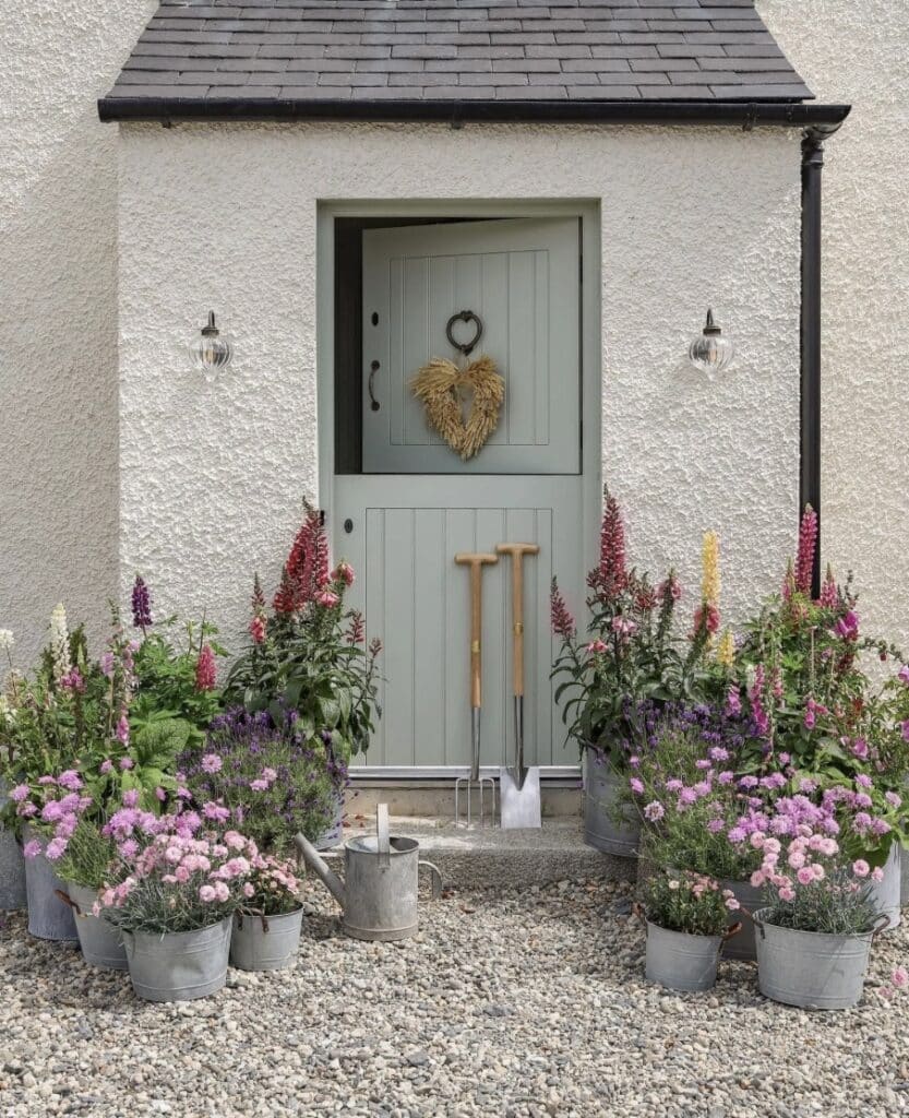 Gravel garden ideas with pots: cottage front door with a gravel base and layered flower-filled containers for an easy, low-maintenance entrance.