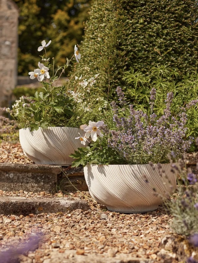Atkin & Thyme green woven daybed on gravel styled with lanterns, grasses and cushions – gravel garden ideas with pots