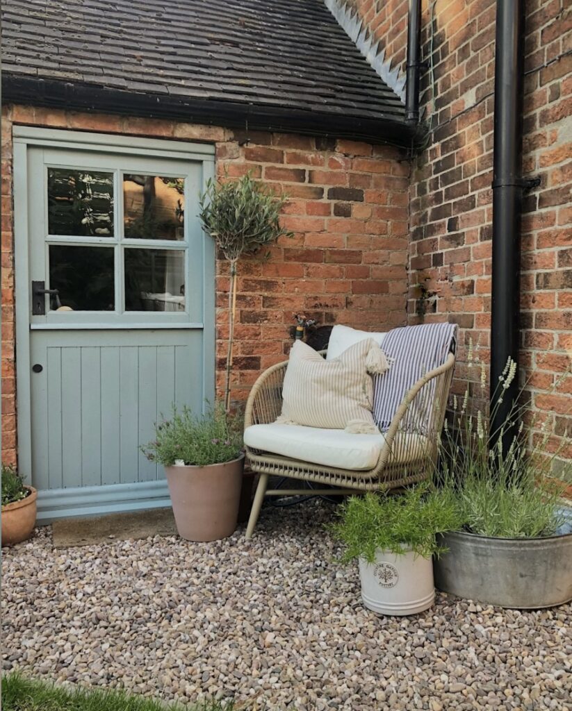 Exterior door painted in Oval Room Blue with a cosy coastal courtyard seating area