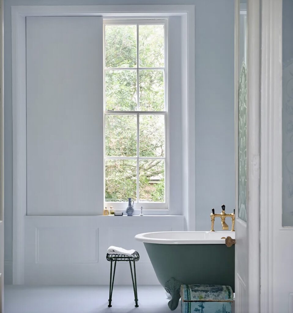 Soft blue bathroom with Kakelugn paint and roll-top bath in a coastal cottage setting