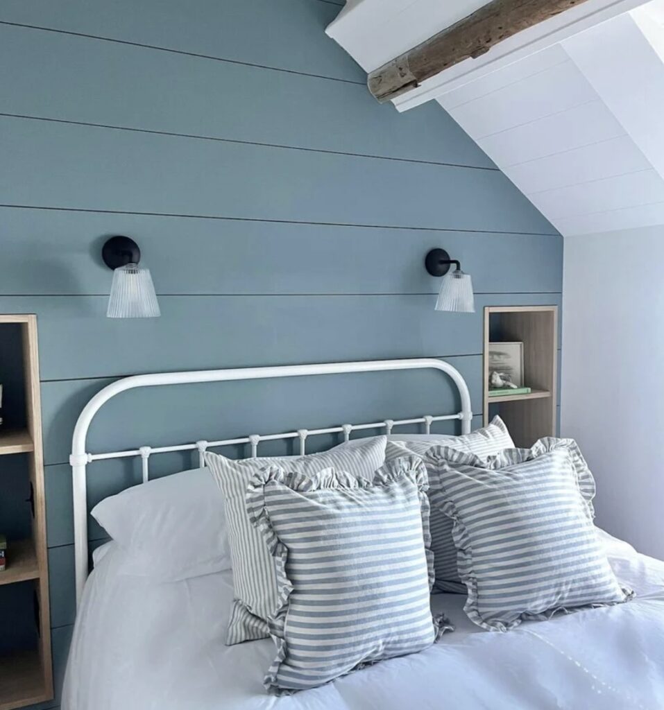 Coastal bedroom painted in Farrow & Ball Selvedge with striped cushions and a white iron bedframe