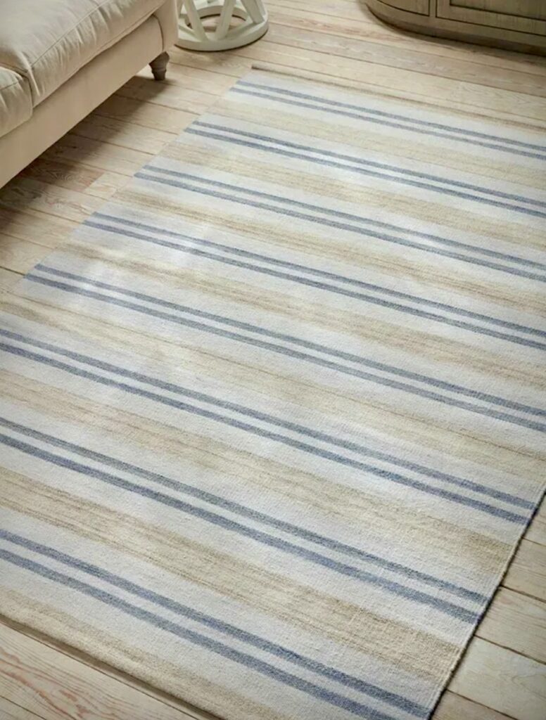 French blue striped rug on pale wooden floors in a relaxed coastal interior design setting