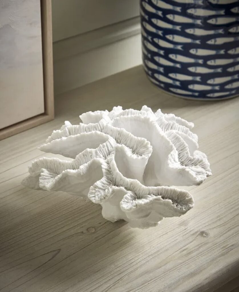 Faux coral ornament styled on a wooden sideboard in a coastal interior design scheme