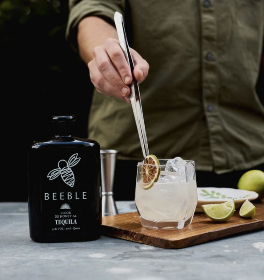 Beeble Honey Tequila margarita — bright coloured margarita recipe with lime wedges and a dried lime garnish on a wooden board