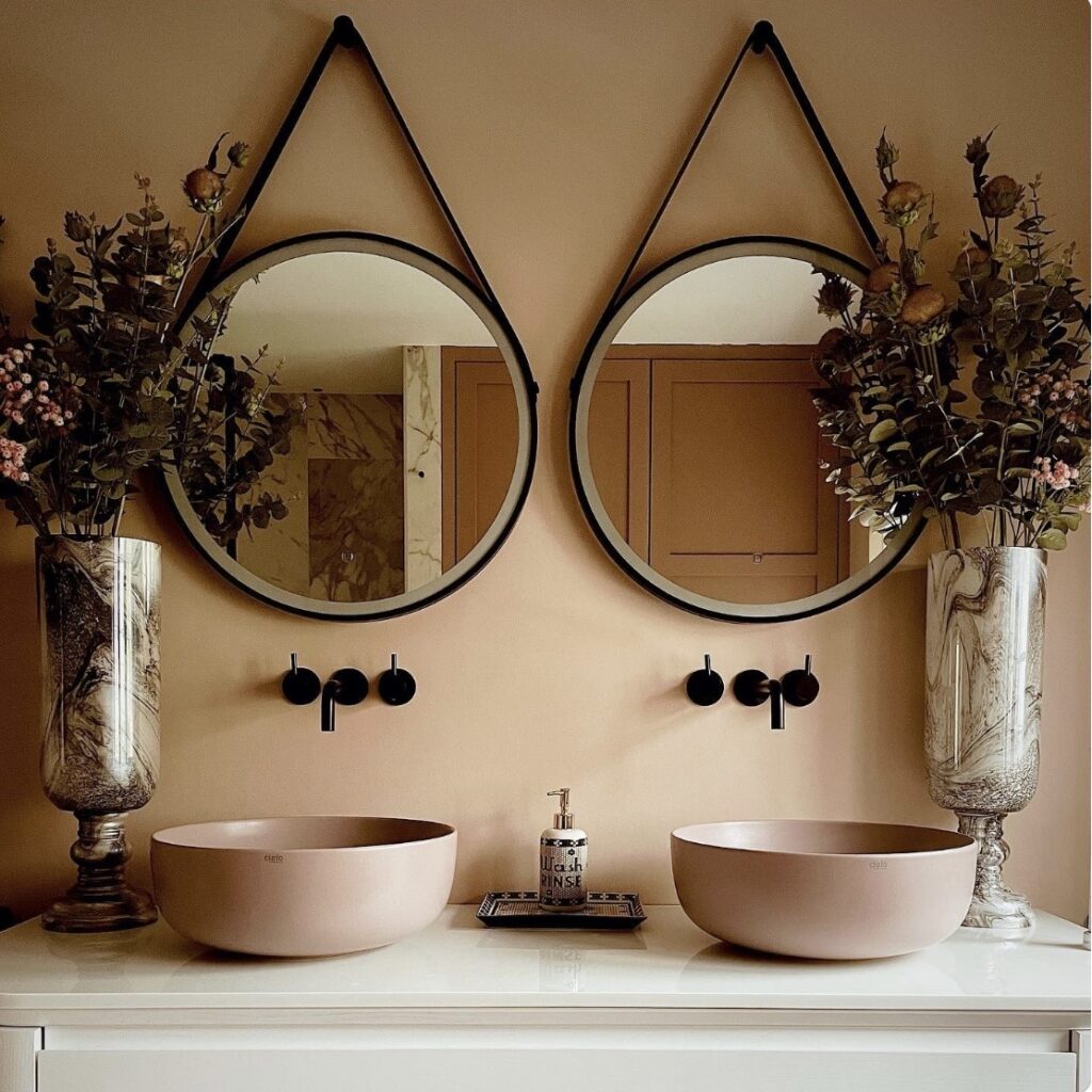 Setting Plaster pink bathroom with blush basins, black mirrors and decorative stone-effect vases