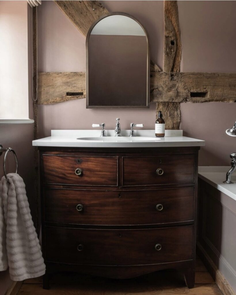 Sulking Room Pink bathroom with an antique dark wood vanity, exposed beams and a traditional basin