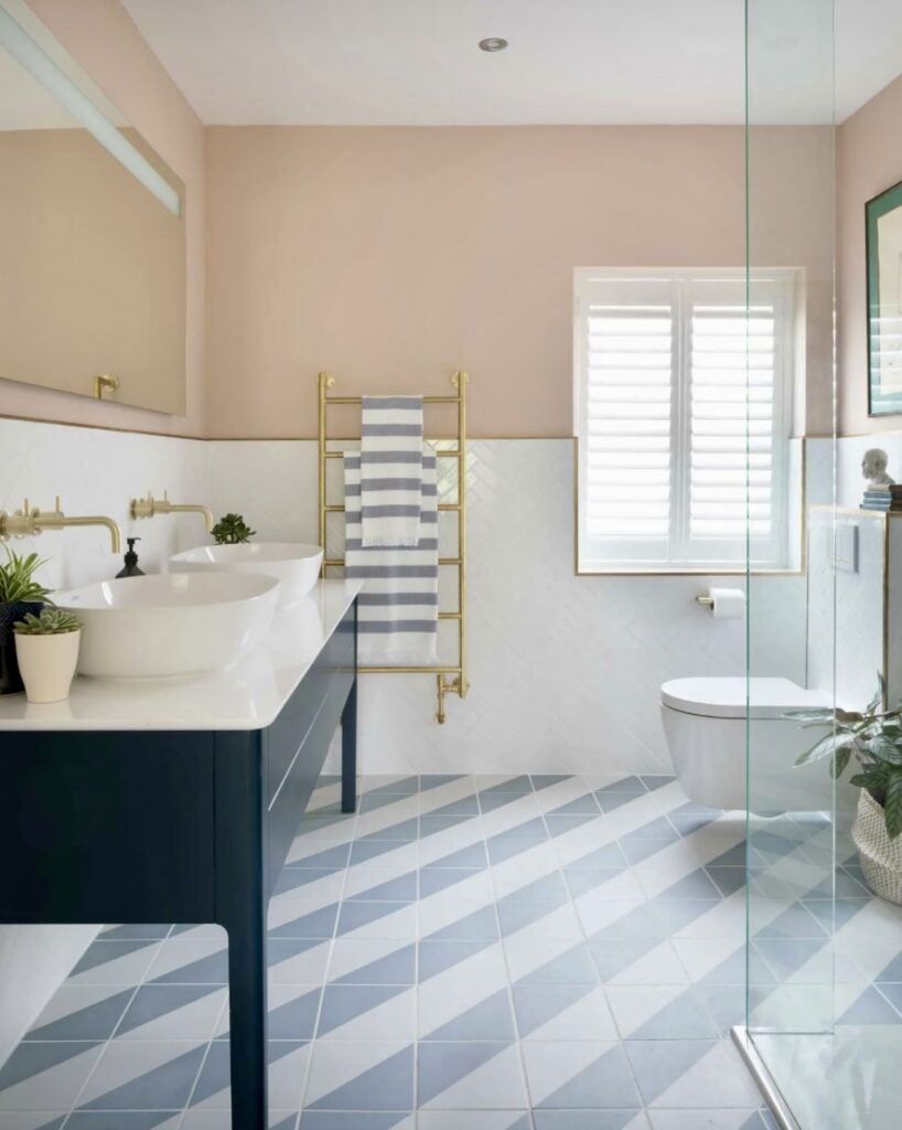 Modern pink bathroom with soft pink bathroom paint, navy vanity, and chevron tiled floor