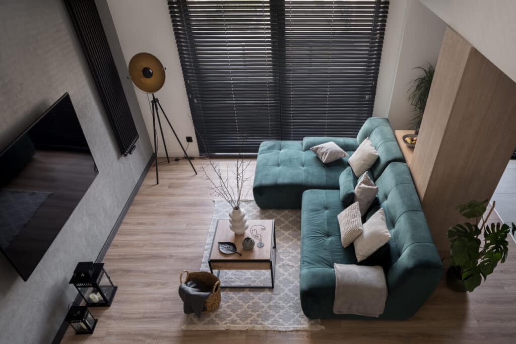 Overhead view of a small living room layout with a sofa on the right, coffee table centred on a rug, and a clear walkway along the left side.