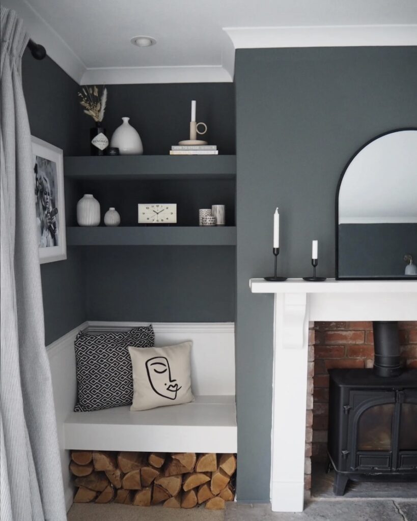 Small living room ideas with Down Pipe painted walls, built-in corner seating, and cosy décor with shelves and a wood burner.