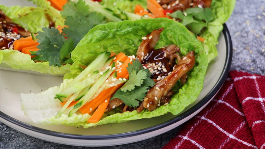 Hoisin chicken lettuce cups with shredded carrot, cucumber, sesame seeds and coriander — a light and flavourful Asian-inspired appetiser.
