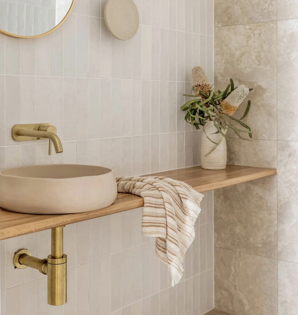Neutral bathroom ideas featuring a slim Scandinavian oak vanity shelf with a round basin, brass tap and pale tiled walls (Image: OhhDarlingDesigns via Etsy)