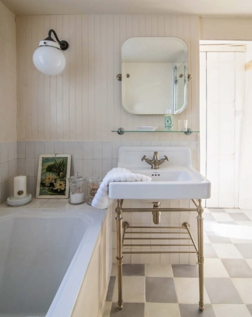 Neutral bathroom ideas in warm oat tones with Farrow & Ball Dimity, tongue-and-groove panelling, brass basin stand and a soft checkerboard floor.
