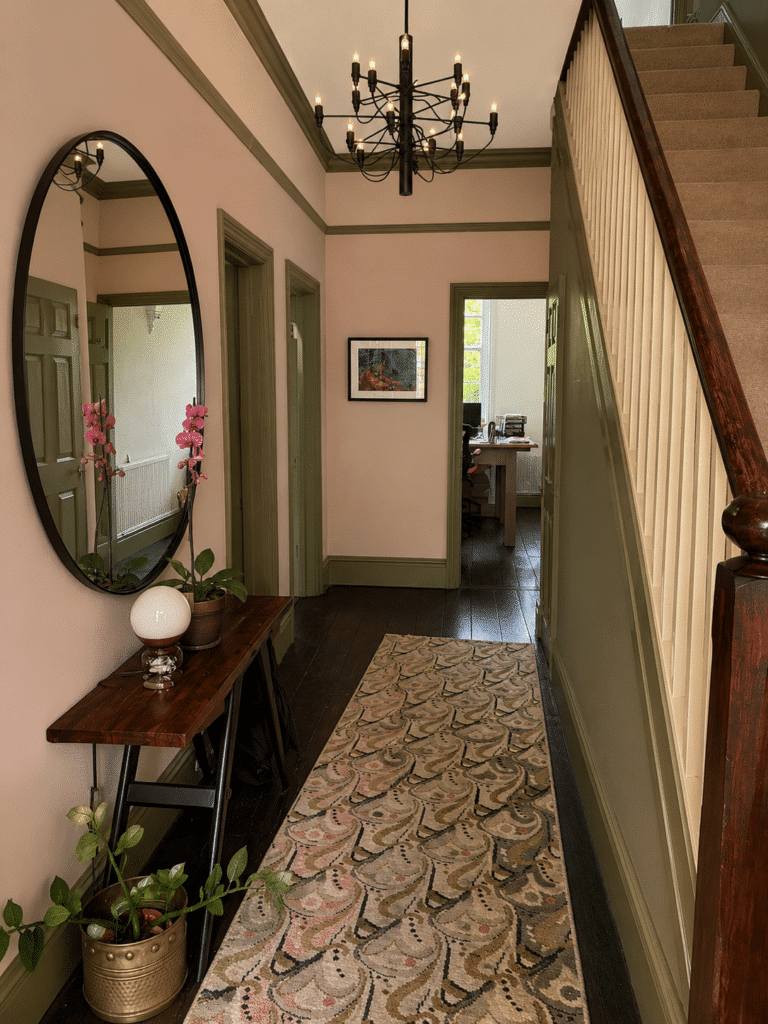 Farrow & Ball Bancha green woodwork and staircase with Setting Plaster pink walls in a hallway