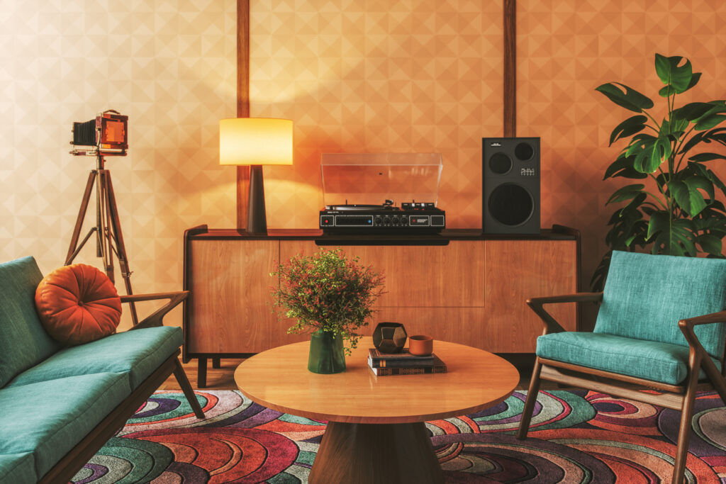 Retro 70s house interior with turquoise chairs, geometric wallpaper, and mid-century wooden furniture