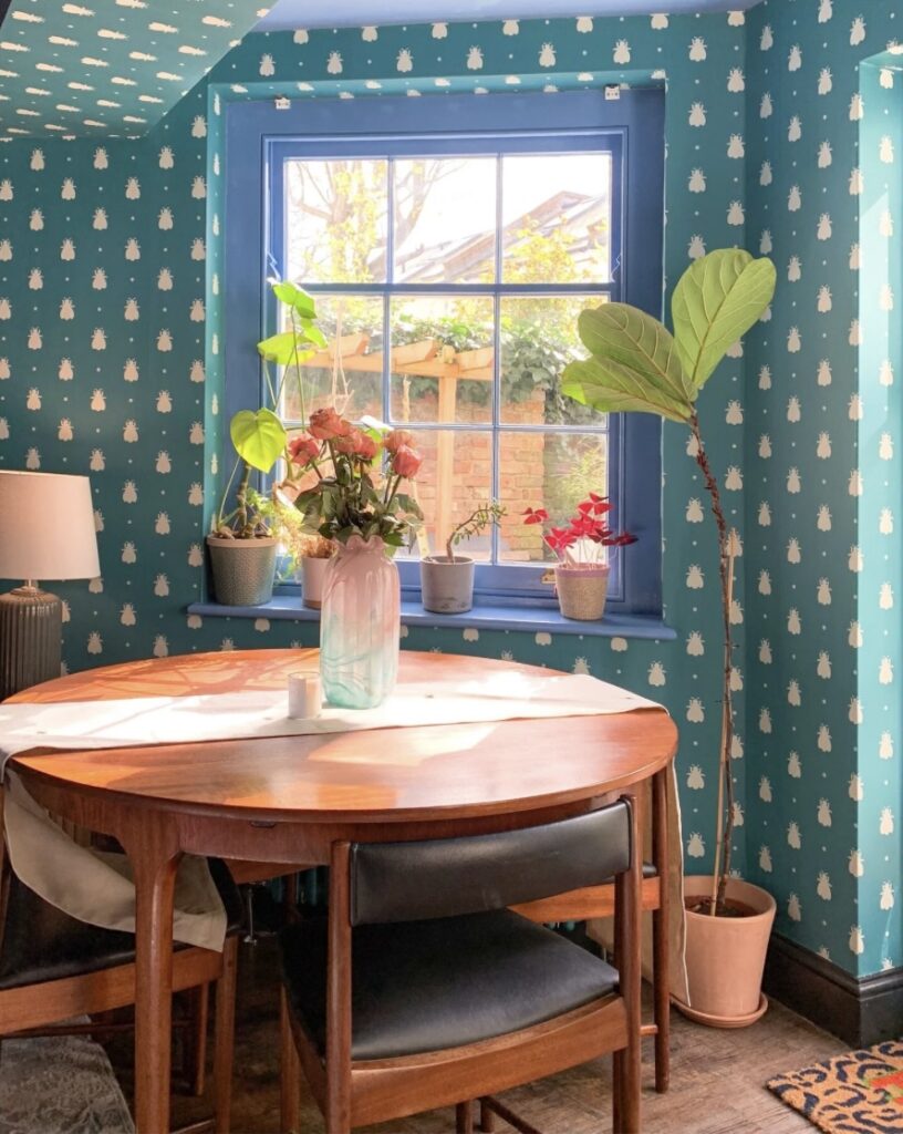 Retro 70s house interior with Cook’s Blue walls, Bumble Bee wallpaper and mid-century dining table