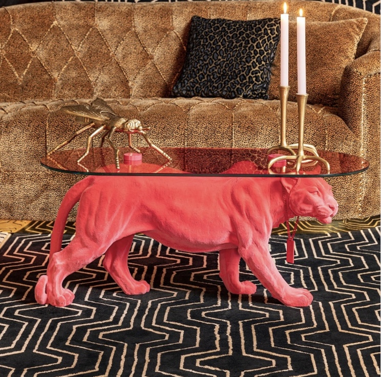 Retro interior design with bold pink panther coffee table, leopard print sofa, and geometric rug