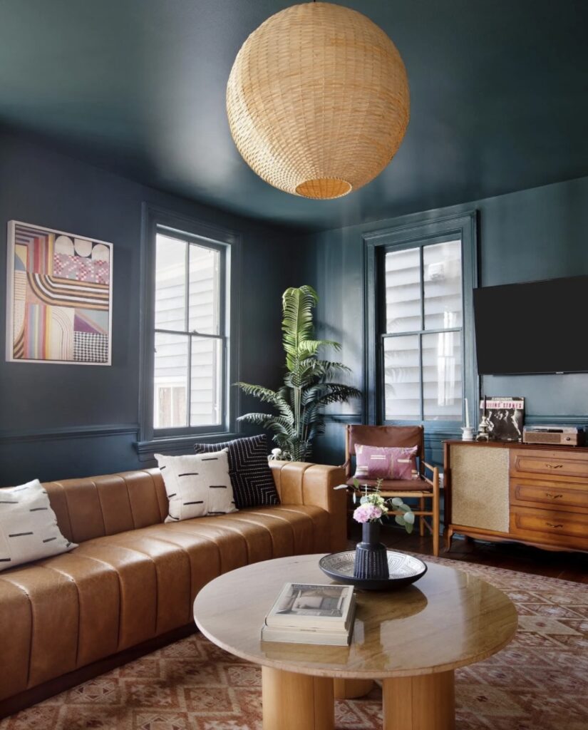 Modern retro interior design with a deep blue living room, mid-century sofa, and wooden furniture