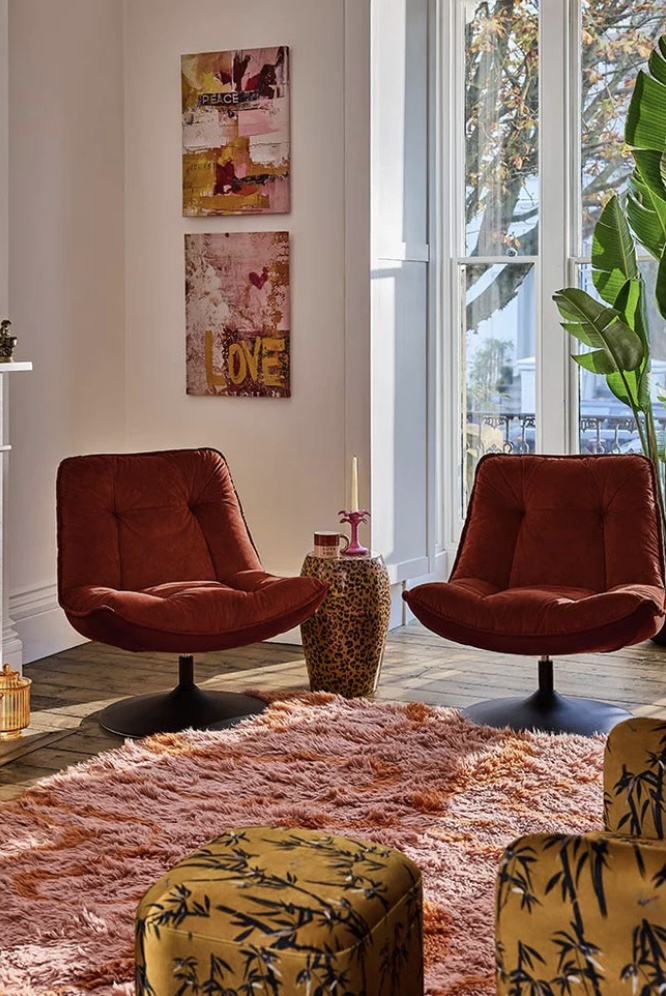 Retro burnt orange swivel chairs with shag rug and colourful art 
