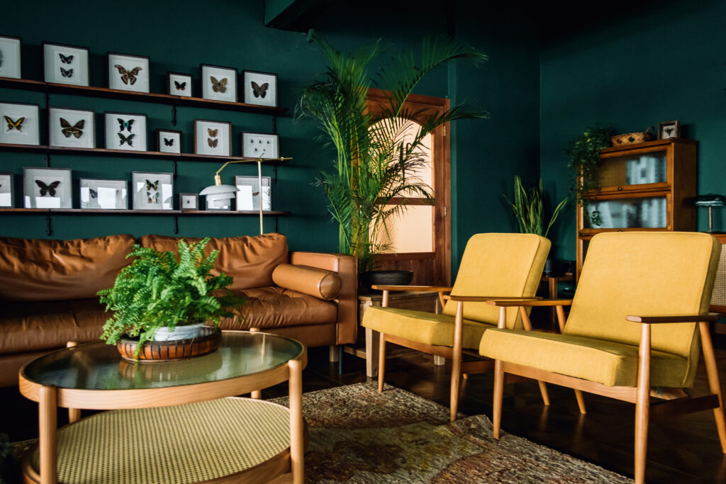 Retro interior design with mustard yellow armchairs, green walls, and mid-century modern furniture
