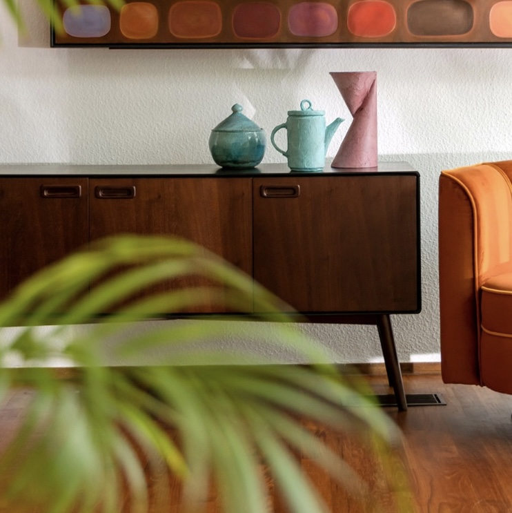 Retro teak sideboard with colourful ceramics and burnt orange sofa