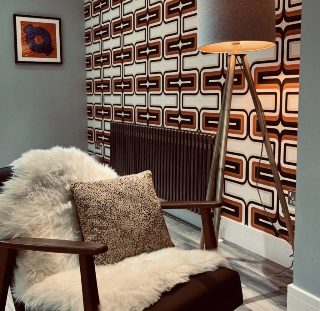 Retro wallpaper design with geometric pattern and cosy armchair in retro interior design 