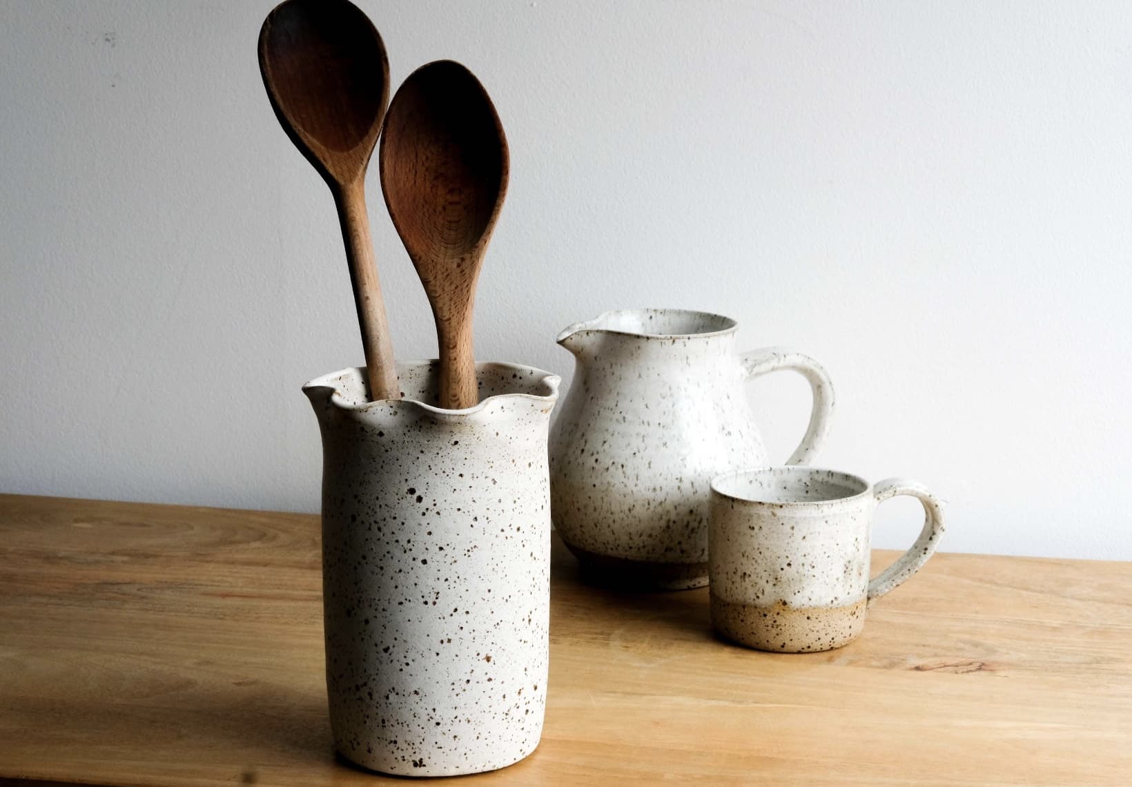 Speckled ceramic utensil jar with wooden spoons