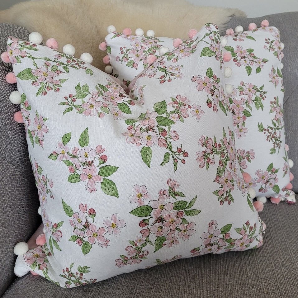 Pink blossom print cushion with pom pom trim by Snugglesandstitch