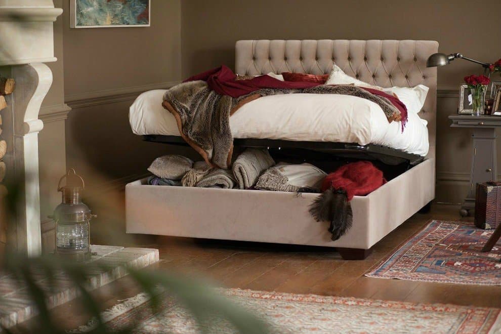 Emilia Ottoman Bed by And So To Bed open to reveal full-depth under-bed storage, styled in a warm neutral bedroom with tufted headboard and layered throws
