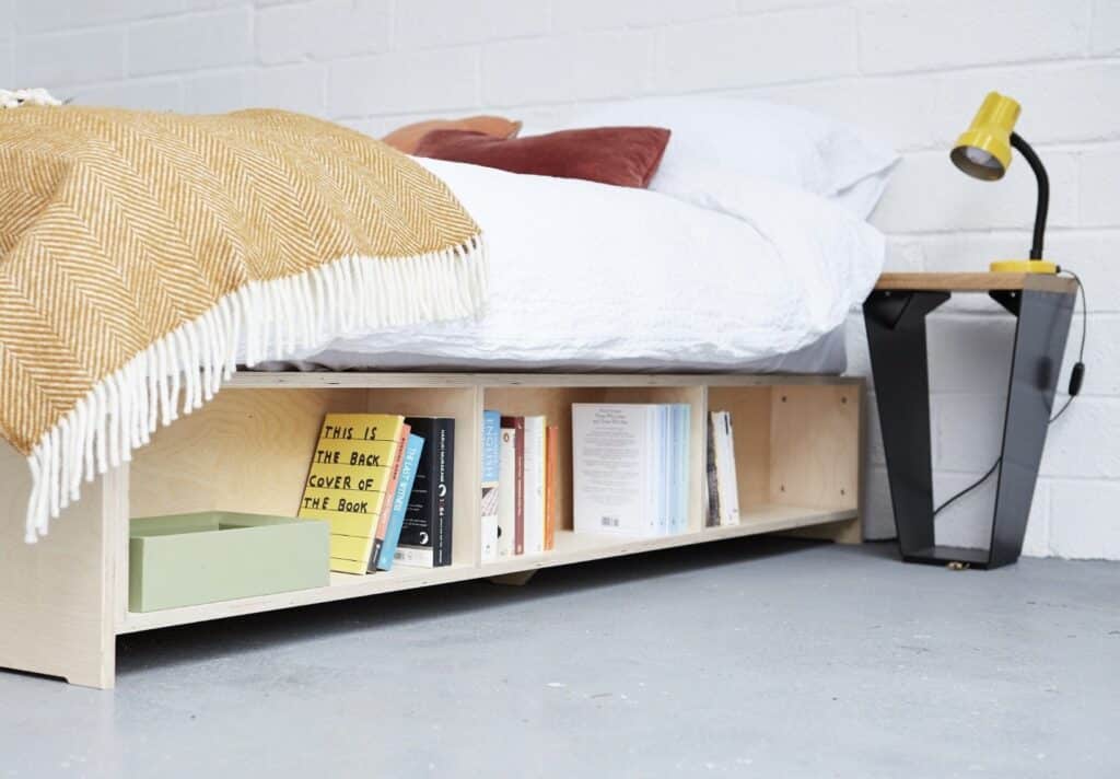 Platform Bookcase Bed by APPLYFurniture — low-profile bed with open bookcase storage built into the base, styled with mustard herringbone throw